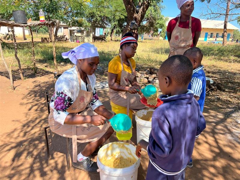 Adults and children involved in an outdoor activity with buckets and containers.