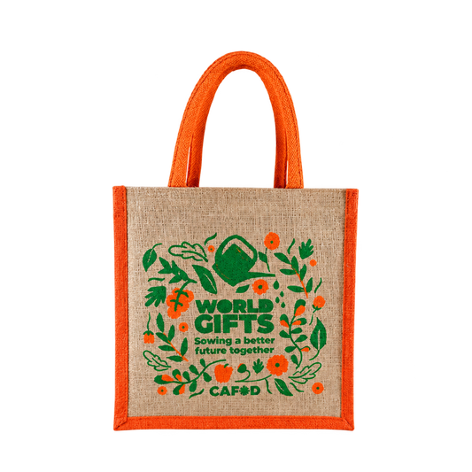Natural jute bag with orange handles and trim and a green and orange CAFOD World Gifts botanical design, on a transparent background.